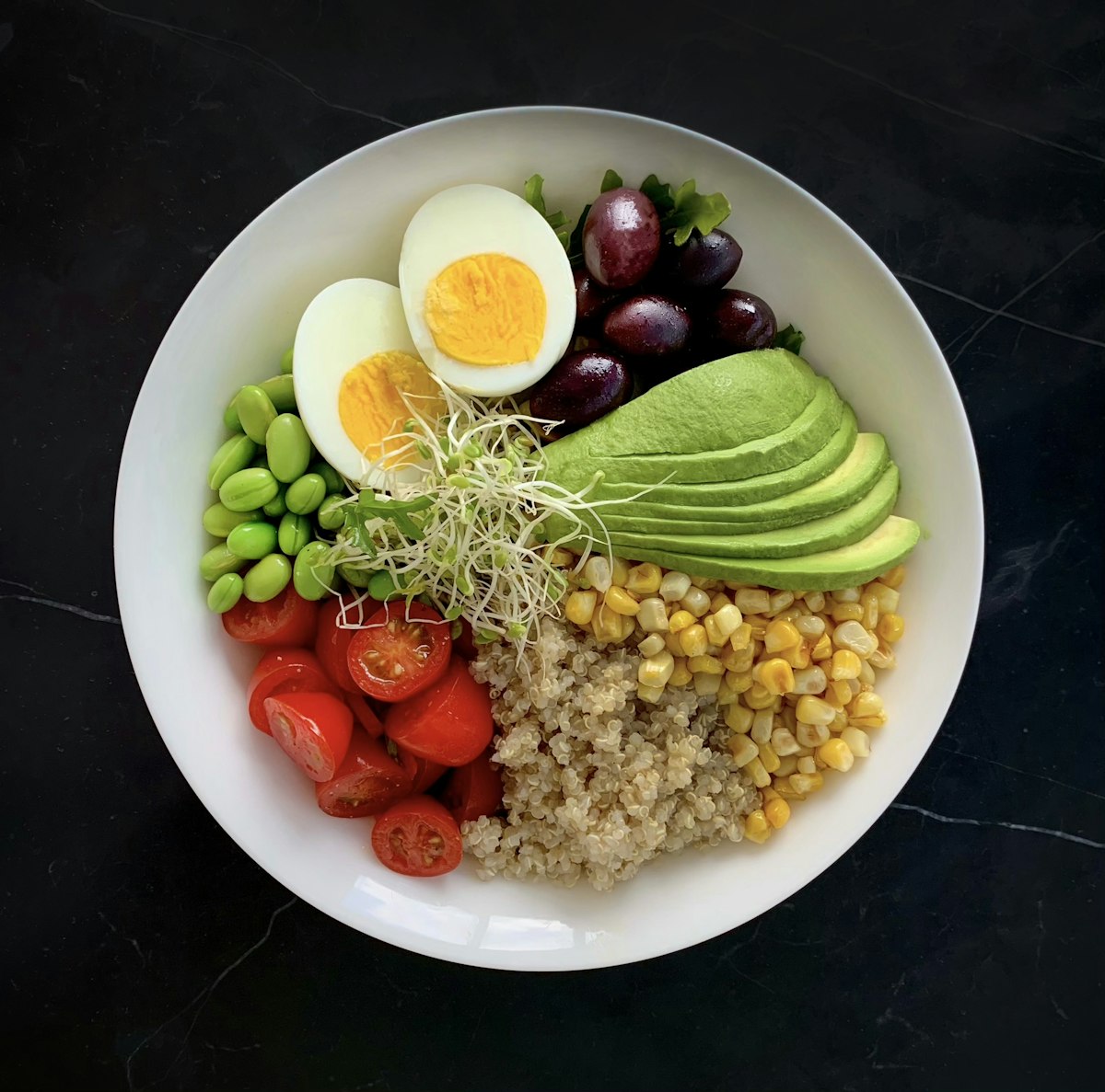 Bol con verduras, huevo, aguacate y otros alimentos variados.